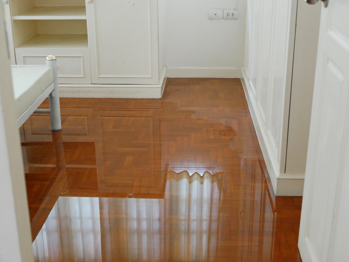 Water spreading / flooding on bedroom parquet floor in a house - damage caused by water leakage