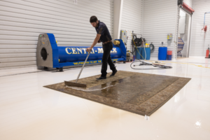 Technician cleaning large rug in industrial facility