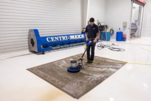 Man cleaning rug with industrial floor buffer