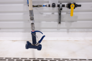 Blue faucet sprayer attached to industrial sink plumbing