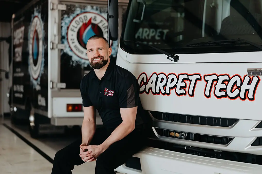Technician sitting beside Carpet Tech service truck